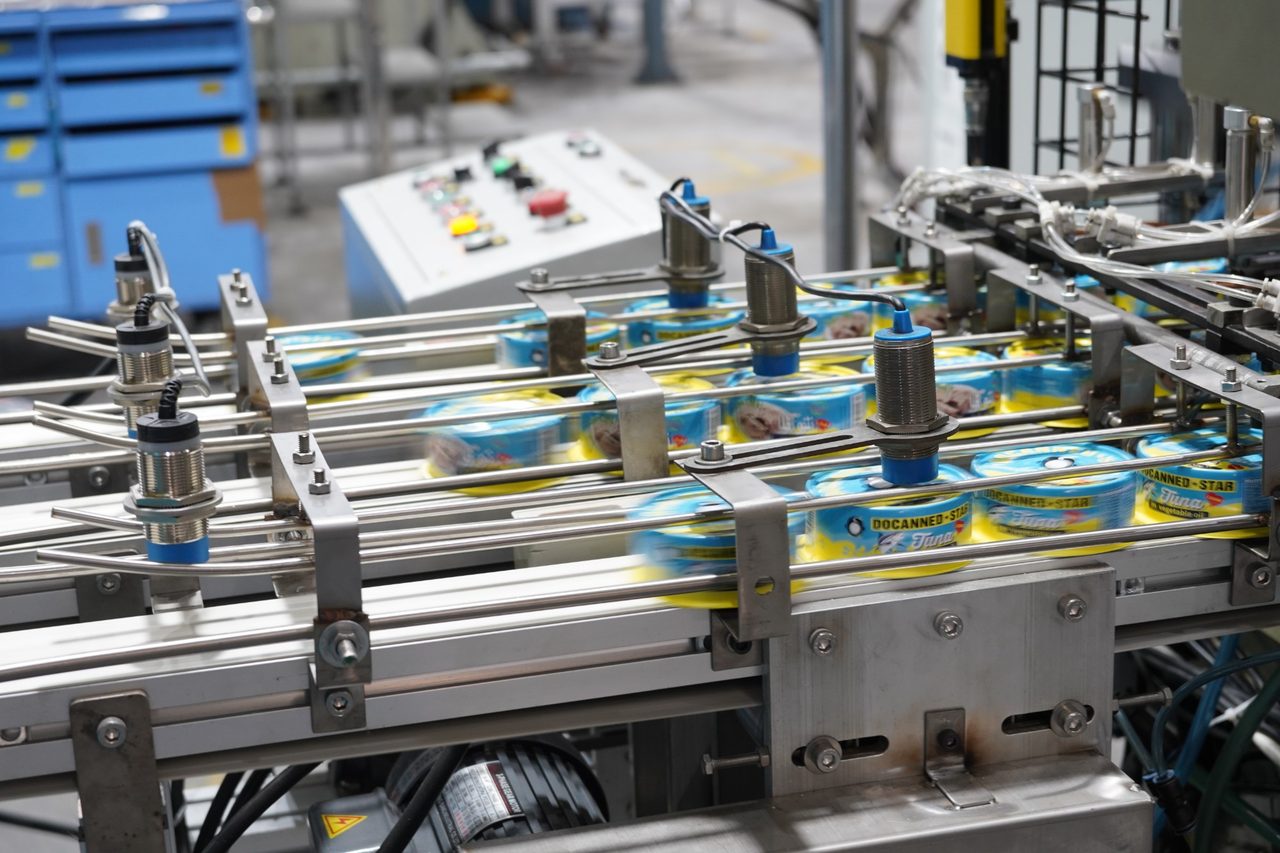 Sealed DocannedStar tuna cans moving along the production line under inspection sensors